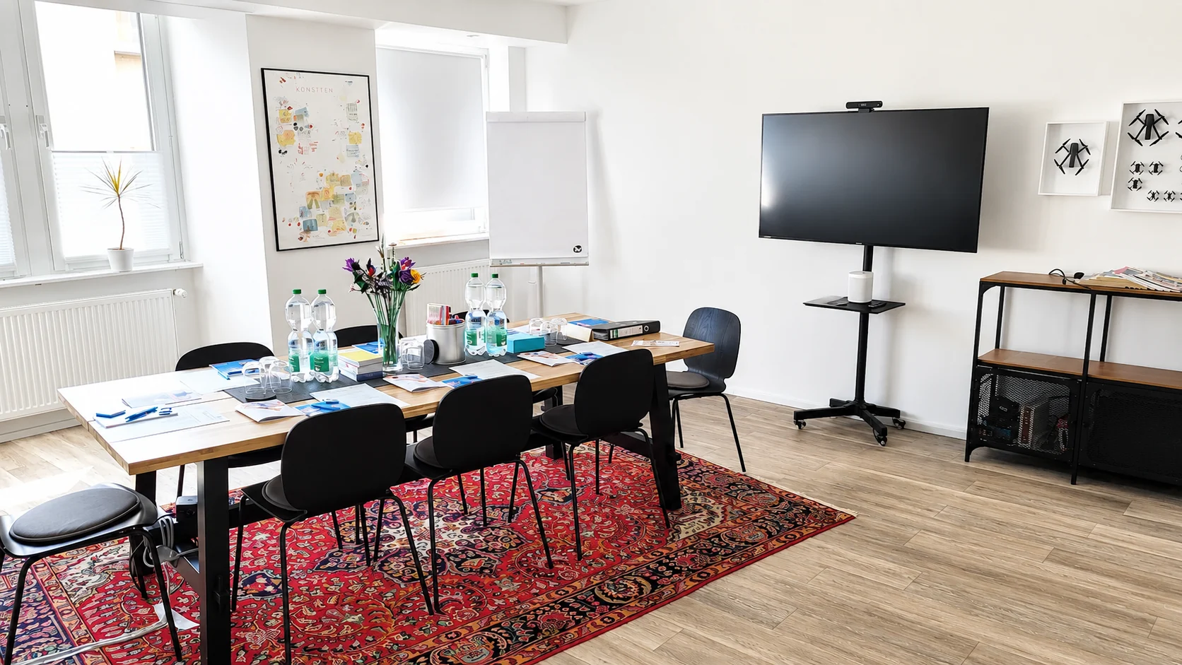 Workshop-Umgebung mit langem Tisch, Bestuhlung, Präsentationsbildschirm und Flipchart für Schulungen im K7 Workspace Königstein